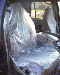 A car seat covered in plastic and sitting on the floor.